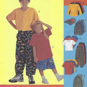 May include: A sewing pattern envelope titled KidStuff featuring illustrations of children wearing V-neck t-shirts, long pants, and shorts with various graphic prints. The pattern includes options for different shirt colors, plaid pants, and skateboard-themed trousers.