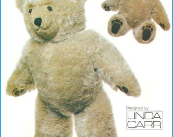 May include: A plush teddy bear with light brown fur, dark eyes, and a black nose. The bear is shown in two positions: standing and sitting. The paws feature dark brown pads. The text "Designed by LINDA CARR" is printed in the bottom right corner.