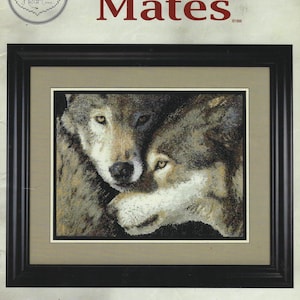 May include: Framed counted cross stitch pattern featuring two wolves, titled "Mates." The artwork depicts the wolves in shades of gray, brown, and white, with a black frame and a tan mat. The text "Cross My Heart" is also visible.