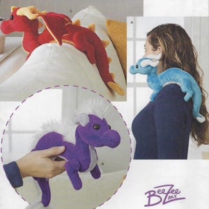 May include: Three plush dragon toys. A red dragon with yellow accents, a blue dragon with white accents, and a purple dragon with white accents. The dragons are all in different poses. The text "BeeZee Art" is visible in the bottom right corner of the image.