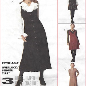May include: A sewing pattern envelope for a jumper dress featuring four variations labeled A, B, C, and D. The cover displays a long black button-front jumper with a white ruffled blouse, alongside other dress styles. Text includes PETITE-ABLE, OVERLOCK/SERGER TIPS, 3 HOUR JUMPER HEURE CHASUBLE, and THE WOMAN'S DAY COLLECTION.