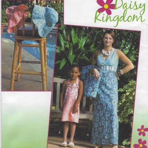 May include: A photo of three people wearing dresses. The woman is wearing a blue and white patterned dress with a white belt. The girl on the left is wearing a pink and white patterned dress. The girl on the right is wearing a blue and white patterned dress. The text "Daisy Kingdom" is in the top right corner of the image.