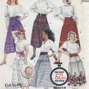May include: A sewing pattern envelope featuring illustrations of six different skirt styles, including solid purple, red paisley, solid red with stripes, white with floral embroidery, blue and white horizontal stripes, and white with polka dots and floral print.