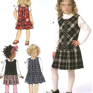 May include: A sewing pattern for a girls' dress with four different variations. The dress is a sleeveless jumper with a skirt. The pattern includes a plaid dress, a floral dress, a solid dress, and a dress with a heart print.