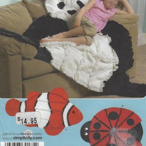 May include: A large panda bear-shaped pillow and blanket set with a child resting on it. The panda is black and white with a ruffled white blanket. Also included are felt cutouts of a red and white clownfish and a red ladybug.