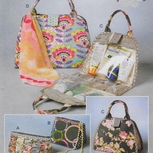 May include: An assortment of fabric handbags with various designs. One bag features a floral pattern with pink, yellow, and purple accents. Another has a black background with pink roses. The image includes the text "Kay Whitt Design".