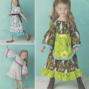 May include: Three children's dresses with different designs. One dress is white with blue floral patterns, another is brown with a bird and leaf pattern, and the third is white with pink accents. All dresses have ruffles.