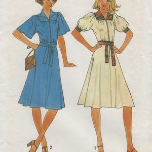 May include: A sewing pattern illustration featuring two dresses. The first is a solid blue dress with short sleeves, a collar, and a tie waist. The second is a cream-colored dress with short puff sleeves, a floral collar, and a matching floral tie waist.
