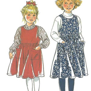 May include: A sewing pattern illustration labeled 9829 featuring two jumper dresses. One is solid red with patch pockets worn over a plaid shirt. The other is a blue floral print with patch pockets worn over a white mock neck top and dark tights.