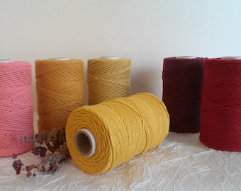 May include: Six spools of cotton rope in various colors, including pink, yellow, and red. The spools are arranged in a row on a white surface.