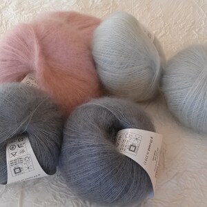 May include: Four skeins of yarn in different colors: light pink, light blue, dark blue, and a darker shade of blue. The yarn is soft and fluffy, and it is perfect for knitting or crocheting.