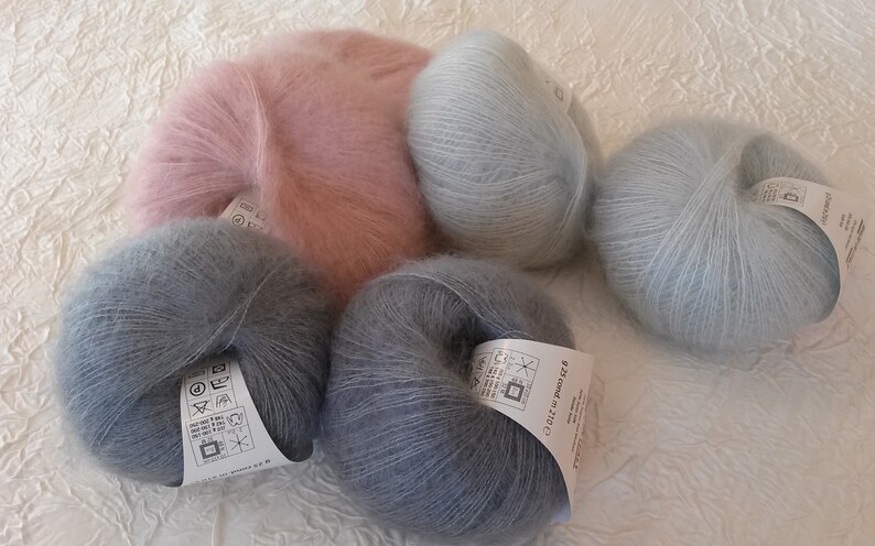 May include: Four skeins of yarn in different colors: light pink, light blue, dark blue, and a darker shade of blue. The yarn is soft and fluffy, and it is perfect for knitting or crocheting.