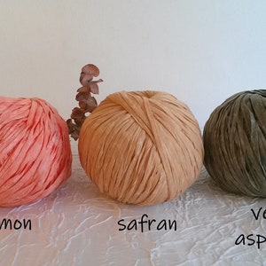 May include: Three balls of yarn in different colors: salmon, saffron, and green. The yarn is made of thin strips of fabric and is arranged in a ball shape.