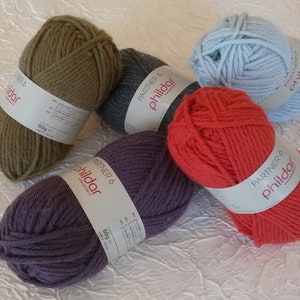 Può includere: Cinque gomitoli di lana in diversi colori: verde oliva, grigio, rosso, viola e azzurro. Ogni gomitolo ha un'etichetta bianca con la scritta "Partner 6 Phildar" stampata su di essa.