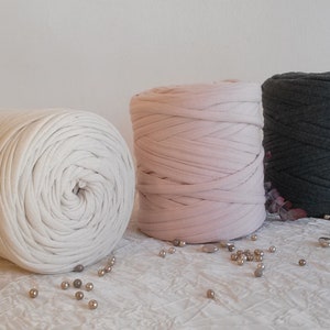 May include: Three spools of yarn in white, pink, and dark grey. The yarn is made of soft, stretchy fabric and is perfect for crafting.