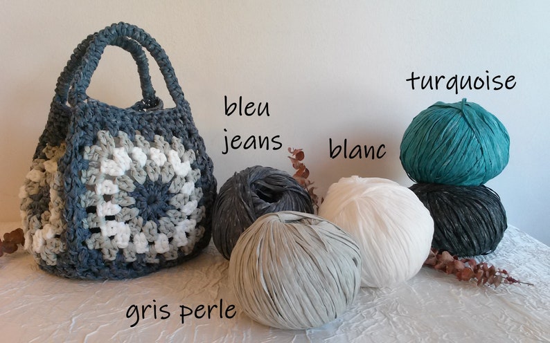 May include: A crocheted tote bag made with recycled t-shirt yarn in shades of gray, white, and turquoise. The yarn balls are labeled "bleu jeans", "blanc", "gris perle", and "turquoise".
