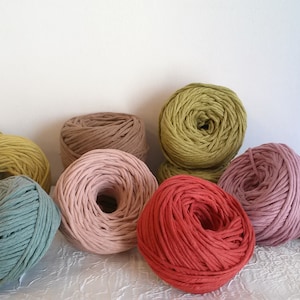 Peut inclure: Assortiment de fils de corde en coton de diff&eacute;rentes couleurs dans des nuances de vert, rose, rouge et marron. Le fil est enroul&eacute; en boules et dispos&eacute; sur une surface blanche.