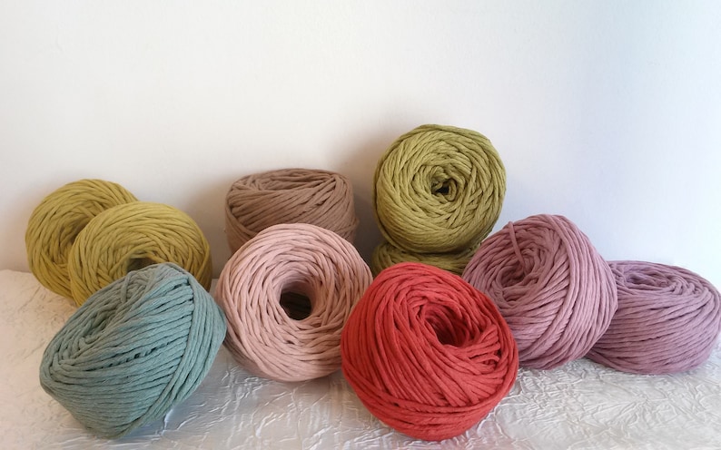 Peut inclure: Assortiment de fils de corde en coton de diff&eacute;rentes couleurs dans des nuances de vert, rose, rouge et marron. Le fil est enroul&eacute; en boules et dispos&eacute; sur une surface blanche.