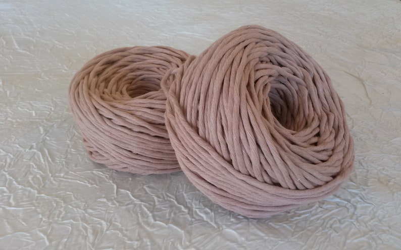 Peut inclure: Deux bobines de corde en coton &eacute;paisse de couleur rose clair. La corde est enroul&eacute;e &eacute;troitement autour d'elle-m&ecirc;me, cr&eacute;ant une forme circulaire.