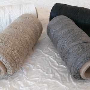 Peut inclure: Quatre bobines de fil de lin ciré en blanc, naturel, gris et noir. Les bobines sont en carton et portent une étiquette en papier.