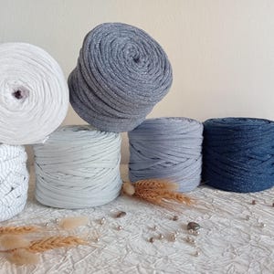 May include: A collection of six yarn balls in various colors, including white, gray, and blue. The yarn is made of soft, textured fabric and is perfect for crafting projects.
