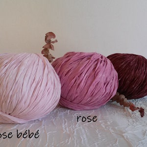 May include: Three balls of yarn in different shades of pink and red. The yarn is a soft, textured material. The colors are labeled "rose b&eacute;b&eacute;", "rose", and "grenat".