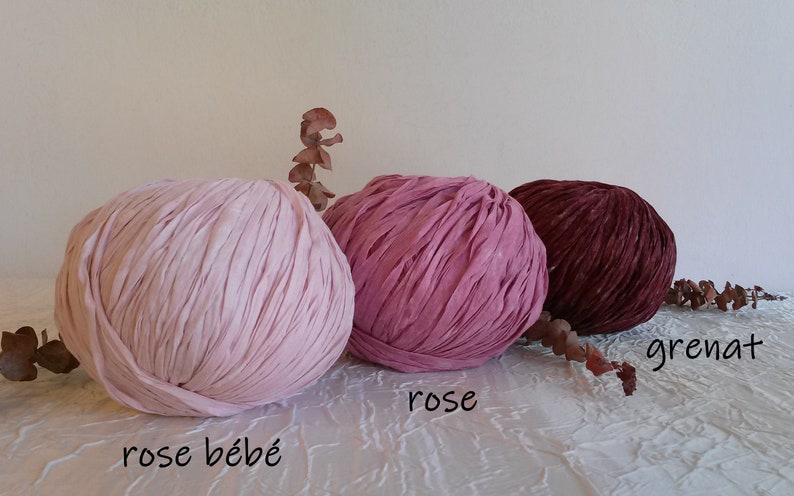 May include: Three balls of yarn in different shades of pink and red. The yarn is a soft, textured material. The colors are labeled "rose b&eacute;b&eacute;", "rose", and "grenat".