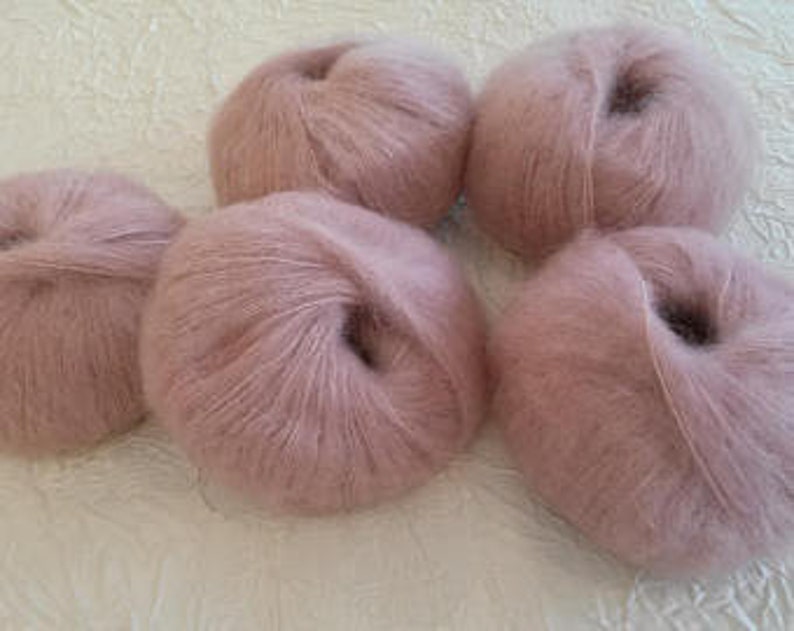 May include: Five balls of pale pink yarn, likely mohair or a similar soft fiber.