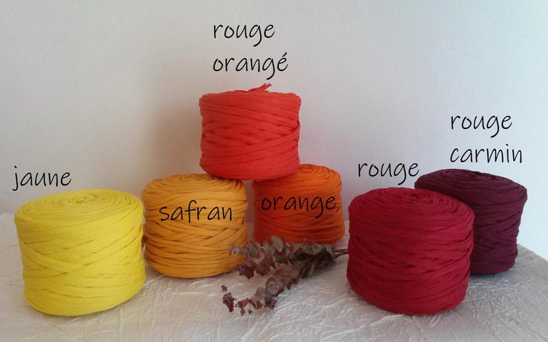 May include: A collection of colorful yarn skeins in shades of yellow, orange, and red. The image includes text labels in French: "jaune", "safran", "orange", "rouge", "rouge carmin", and "rouge orang&eacute;".