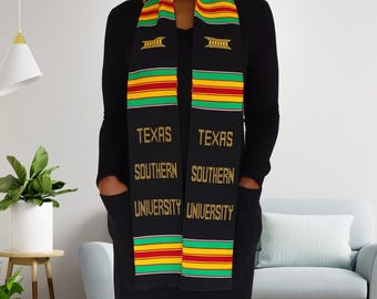 May include: Black graduation stole with gold lettering that reads "Texas Southern University". The stole has green, red, and yellow stripes.
