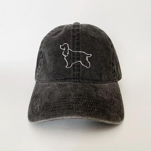 May include: A black baseball cap with a white embroidered outline of a cocker spaniel.