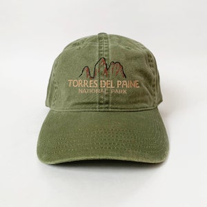 May include: A green baseball cap with an embroidered logo that says "Torres del Paine National Park" with a mountain range graphic.