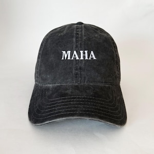 Könnte beinhalten: Eine schwarze, abgenutzte Baseballkappe aus Baumwolle mit weiß gesticktem Text, der "MAHA" lautet.