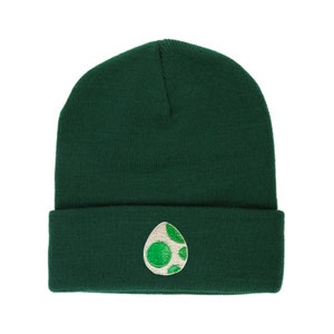May include: A dark green beanie with a white and green embroidered egg design.