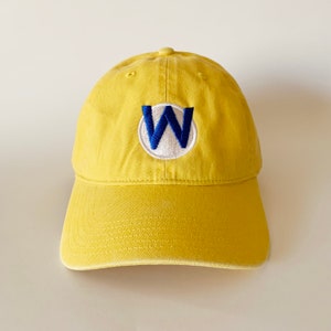 May include: A yellow baseball cap with a blue and white embroidered letter W in a circle on the front.