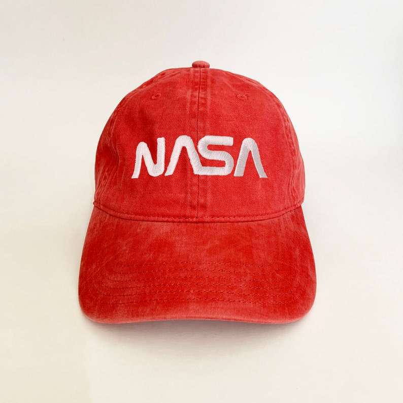 May include: A red baseball cap with a white embroidered NASA logo.