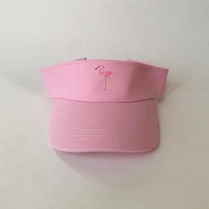 May include: A pink visor with a flamingo embroidered on the front.