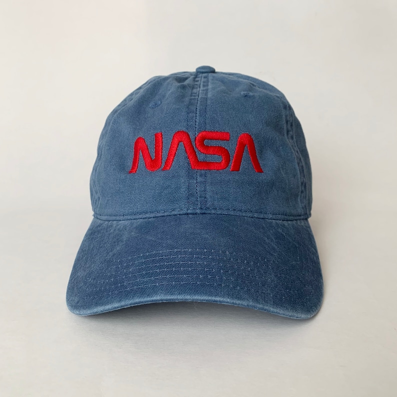 May include: A blue denim baseball cap with a red embroidered NASA logo.