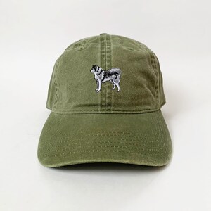 May include: A green baseball cap with an embroidered image of a husky dog.