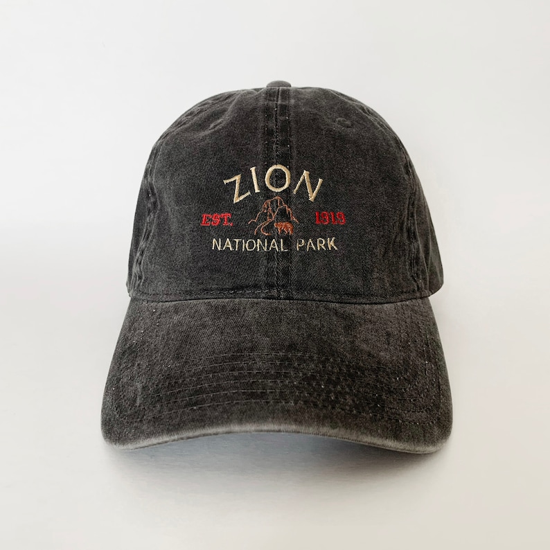 May include: A black distressed baseball cap with an embroidered logo that reads "Zion National Park Est. 1919".