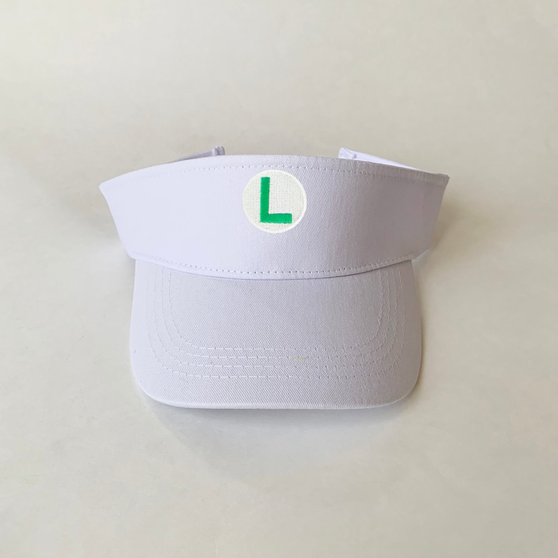 Op de afbeelding: Witte visor met een groene letter L in een witte cirkel aan de voorkant.
