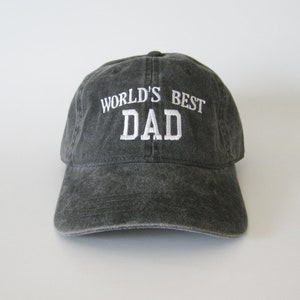 May include: A black washed cotton baseball cap with white embroidered text that reads "WORLD'S BEST DAD".