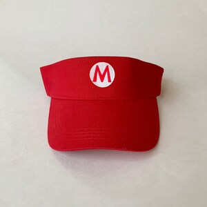 Op de afbeelding: Rode visor met een witte cirkel en een rode "M" in het midden.