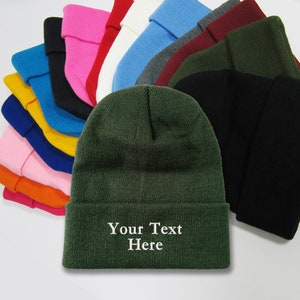 May include: A stack of various colored knit beanies with a green beanie in the front. The green beanie has white text that reads "Your Text Here".