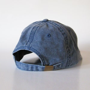 Puede incluir: Una gorra de b&eacute;isbol de mezclilla azul con un cierre de hebilla de lat&oacute;n en la parte posterior.