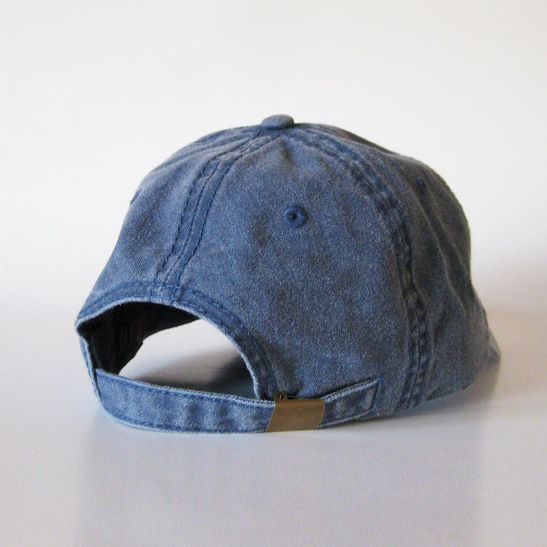 Puede incluir: Una gorra de b&eacute;isbol de mezclilla azul con un cierre de hebilla de lat&oacute;n en la parte posterior.