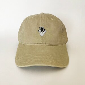 Puede incluir: Una gorra de b&eacute;isbol de color caqui con un perro border collie blanco y negro bordado en la parte delantera.