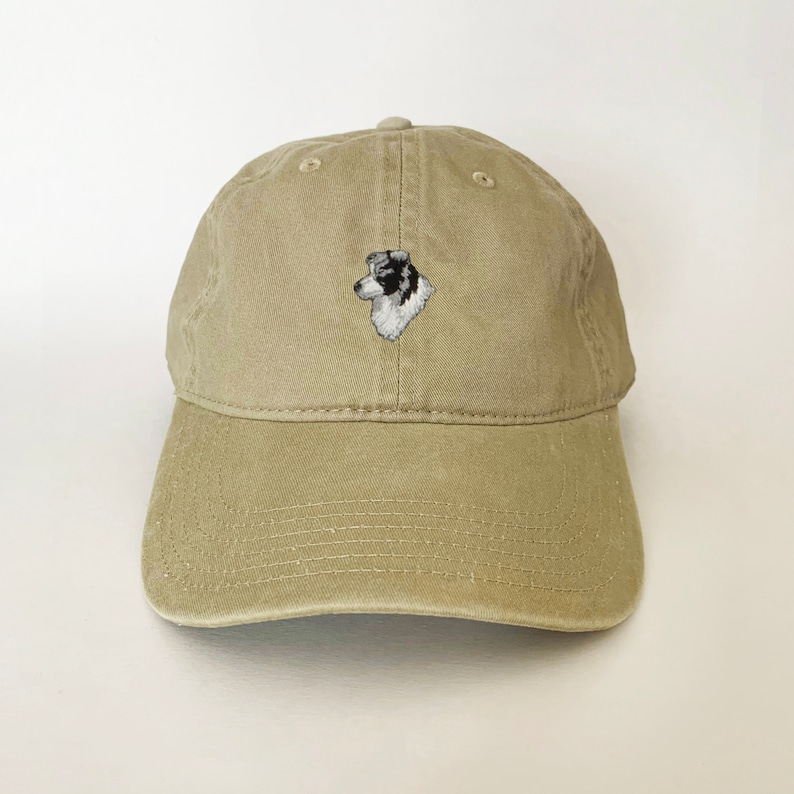 Puede incluir: Una gorra de b&eacute;isbol de color caqui con un perro border collie blanco y negro bordado en la parte delantera.