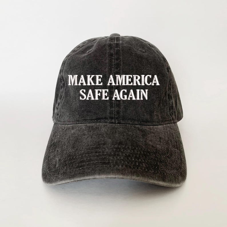 May include: A black, distressed baseball cap with the white text "MAKE AMERICA SAFE AGAIN" across the front. The cap has a curved brim and a classic six-panel design, suitable for casual wear.