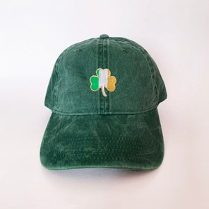 May include: A green baseball cap with an embroidered shamrock featuring the colours of the Irish flag.